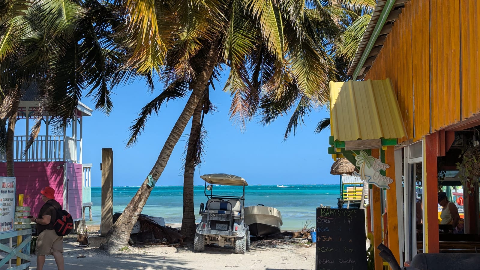 Palm trees, golf cart, and colorful buildings on Caye Caulker