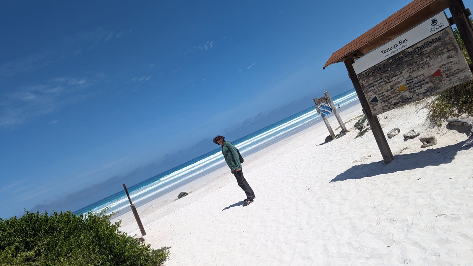 A lone traveler standing on the wide white sand of Tortuga Bay, Santa Cruz, Galápagos