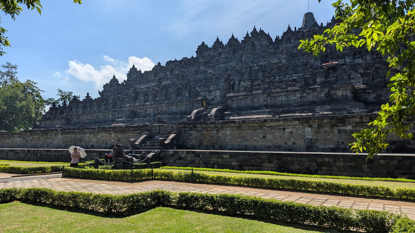 Full facade of Borobudur temple with a tourist for scale