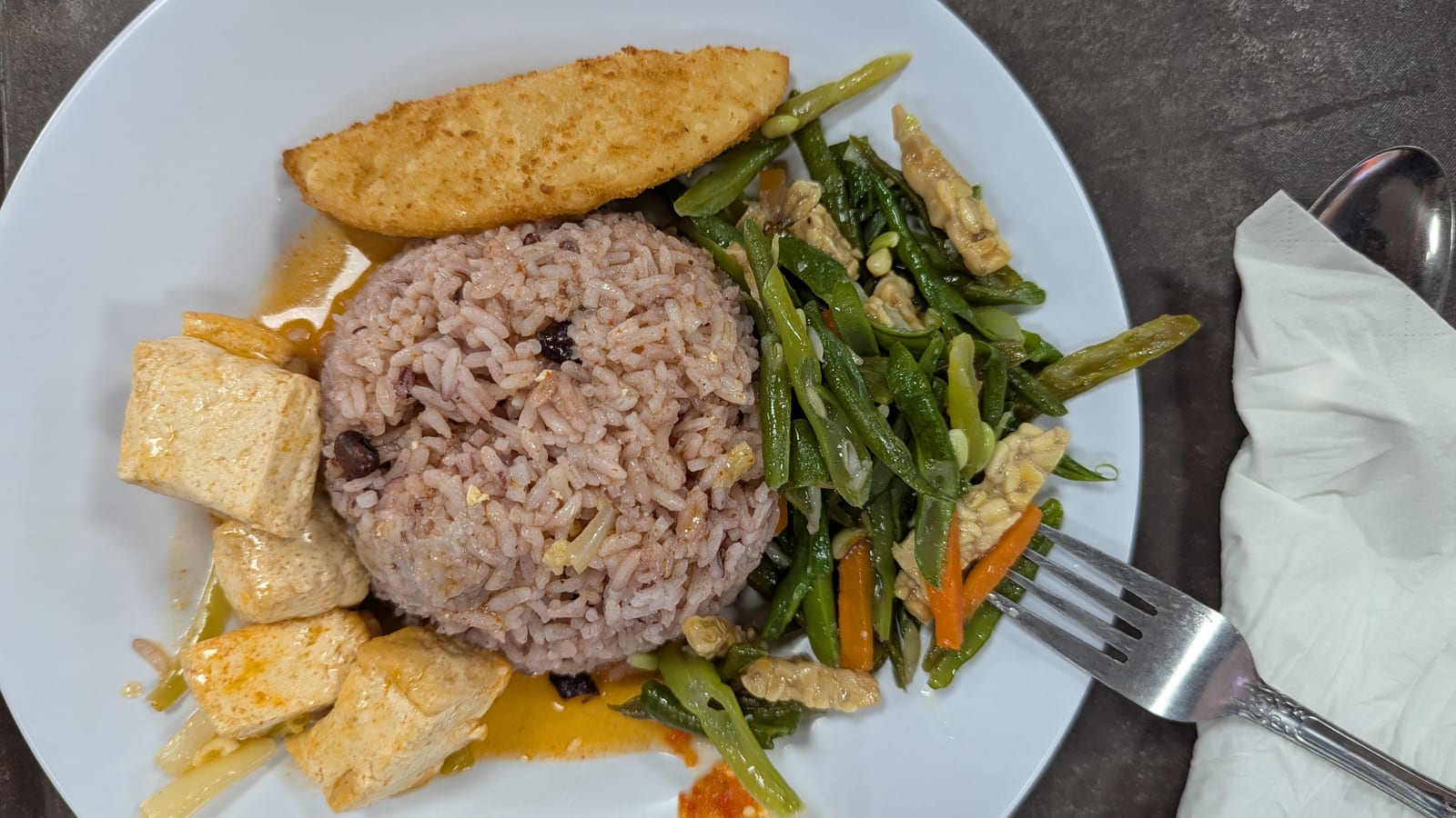A plate of rice, tofu, and stir-fried greens in Dili