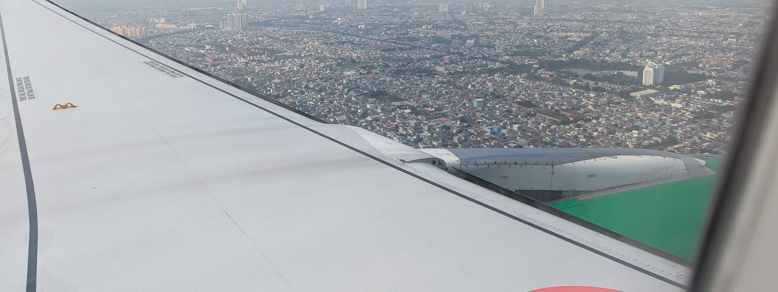 Jakarta skyline seen past the wing of a landing plane