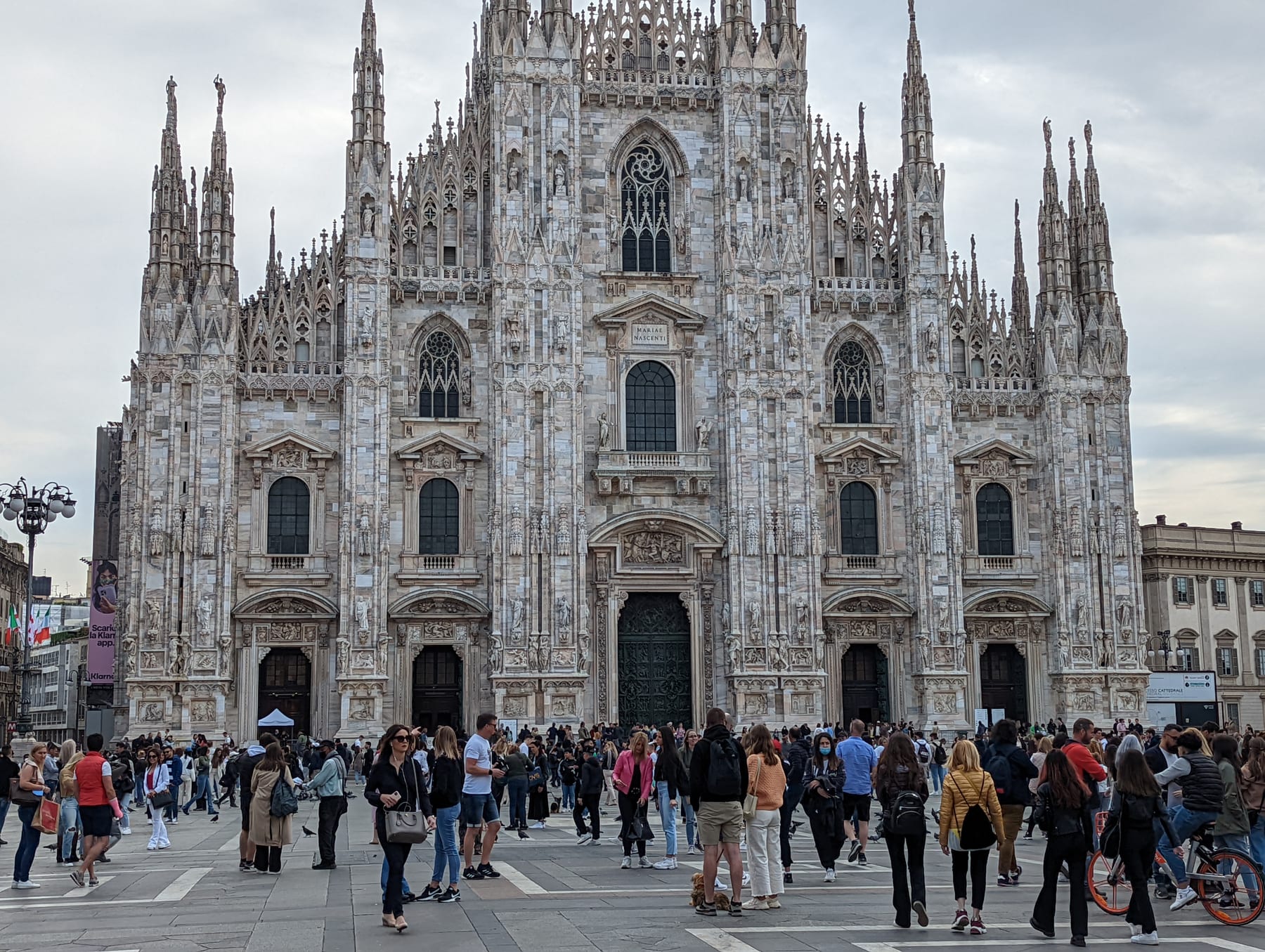 The elaborate white marble facade of Milan Cathedral seen from the piazza